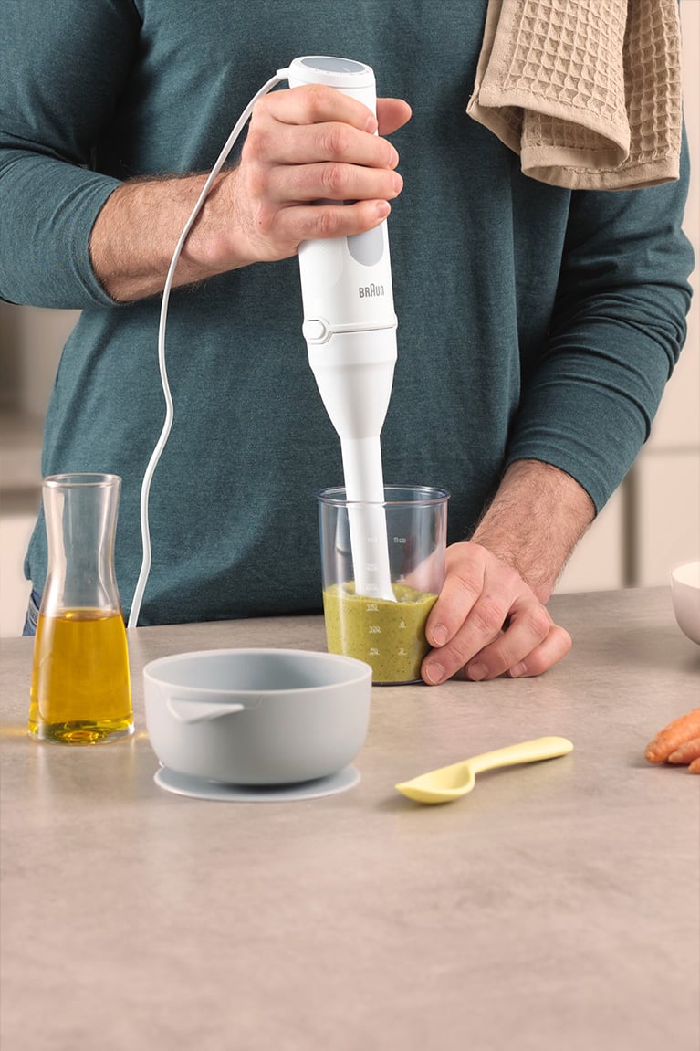 Man at the kitchen counter preparing a vegetable mash with the Braun MultiQuick 5 with Small Portion Shaft accessory.