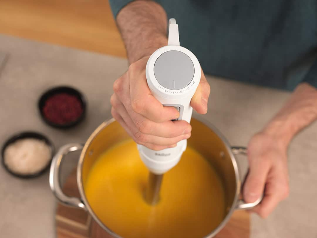 Man preparing a soup with the Braun MultiQuick Hand blender, view from above into the pot.