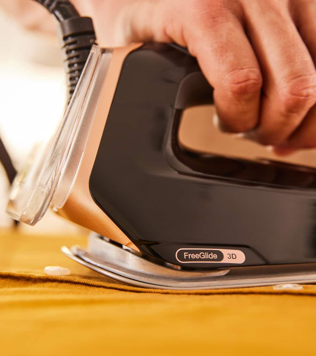 Braun CareStyle 9 steam generator iron glides backwards over a button of a yellow shirt