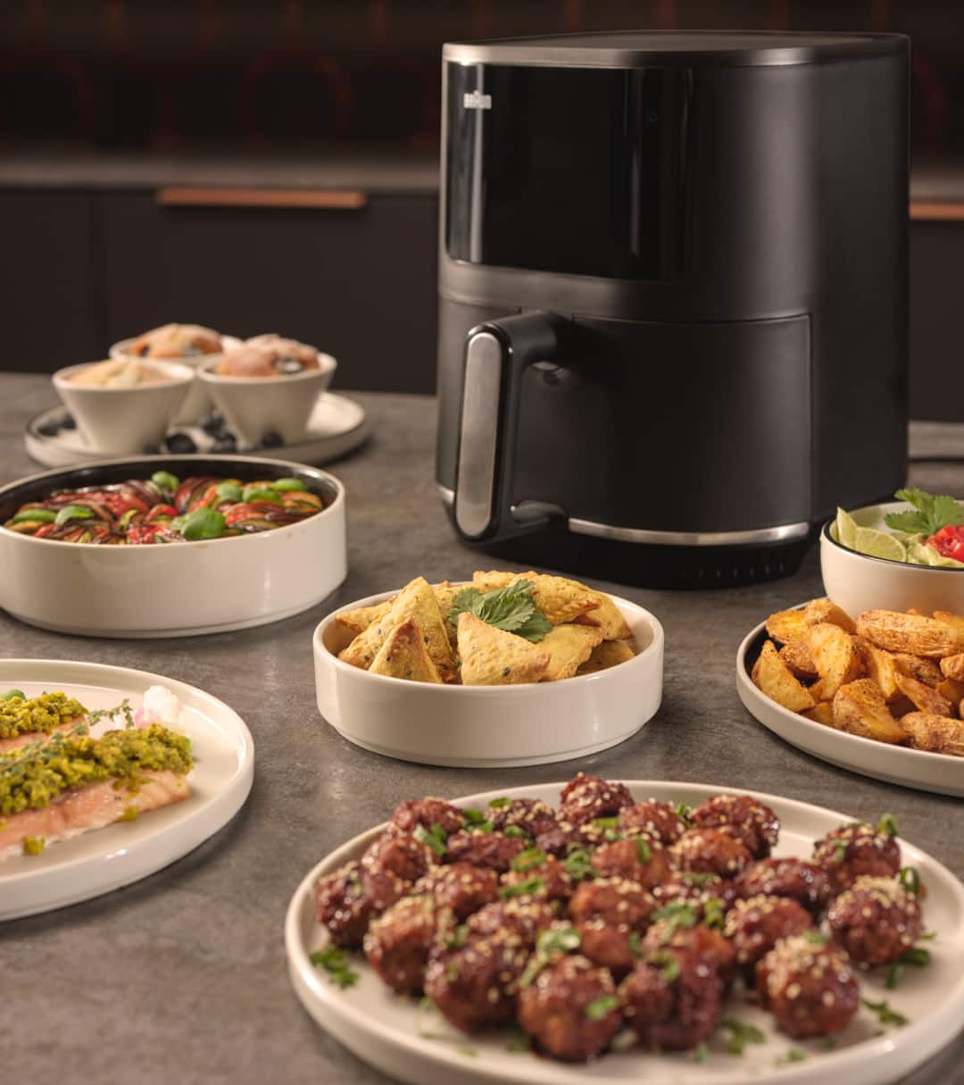 Braun MultiFry 3 airfryer standing on top of a kitchen counter with various dishes such as Samosas and Köttbullar around