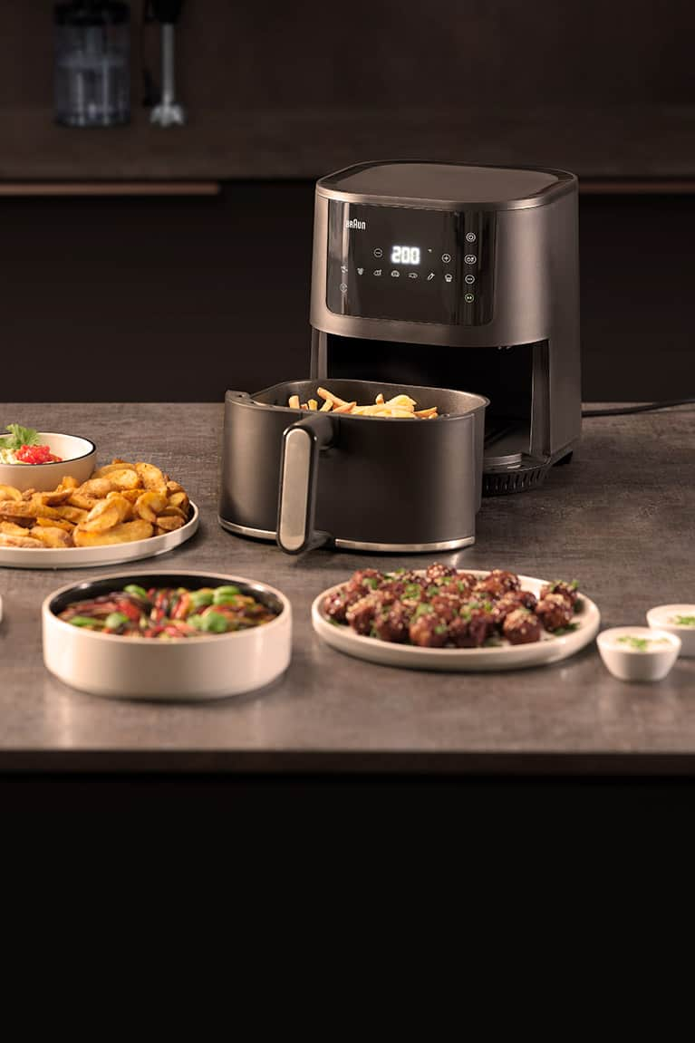 Braun MultiFry 3 airfryer standing on top of a kitchen counter with various dishes around