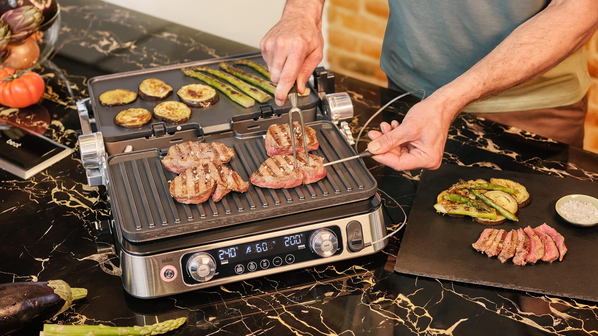 A man grilling steak alongside colorful vegetables