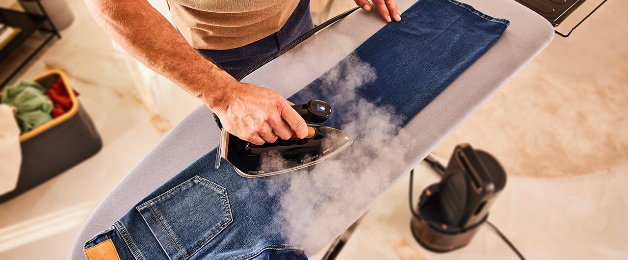 Man ironing jeans with Braun CareStyle 9 Steam generator iron